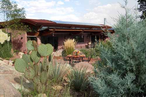 Landscaped view of the south side of a Poured Earth home with the photo-voltaic system well-integrated onto the metal roof